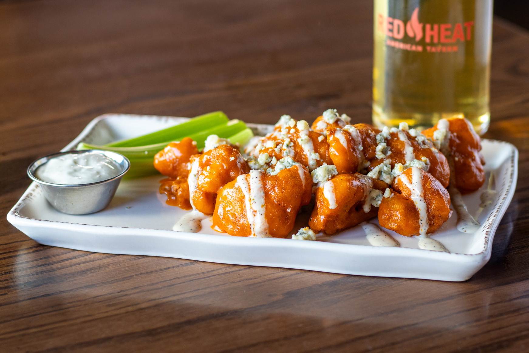 Buffalo cauliflower topped with blue cheese sauce and a side of celery