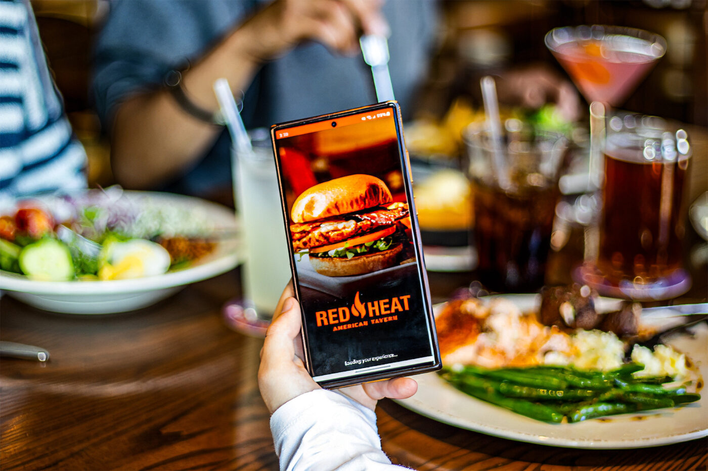 Red Heat American Tavern app with a table full of food in the background