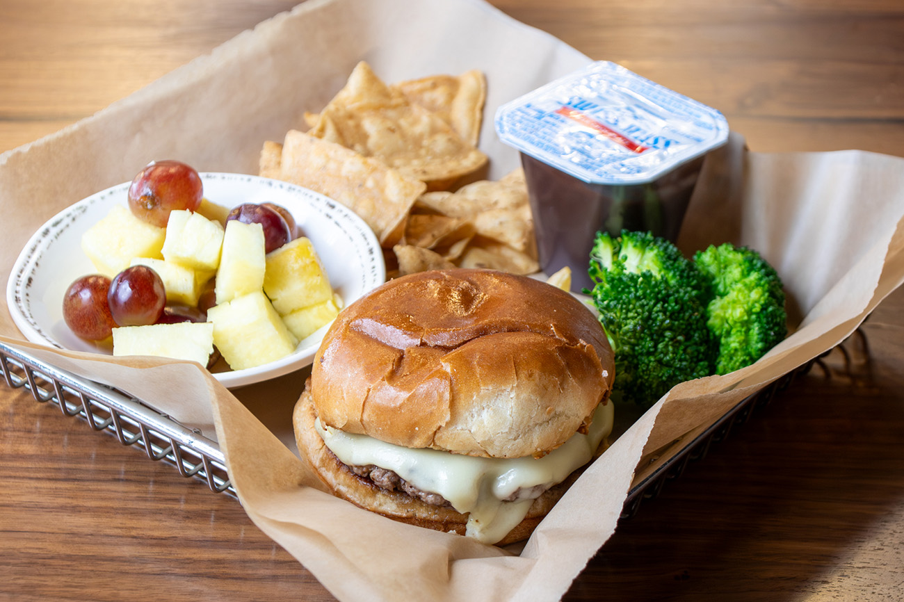 Kids Meal with a cheeseburger, side of broccoli, fruit, chips and a pudding cup