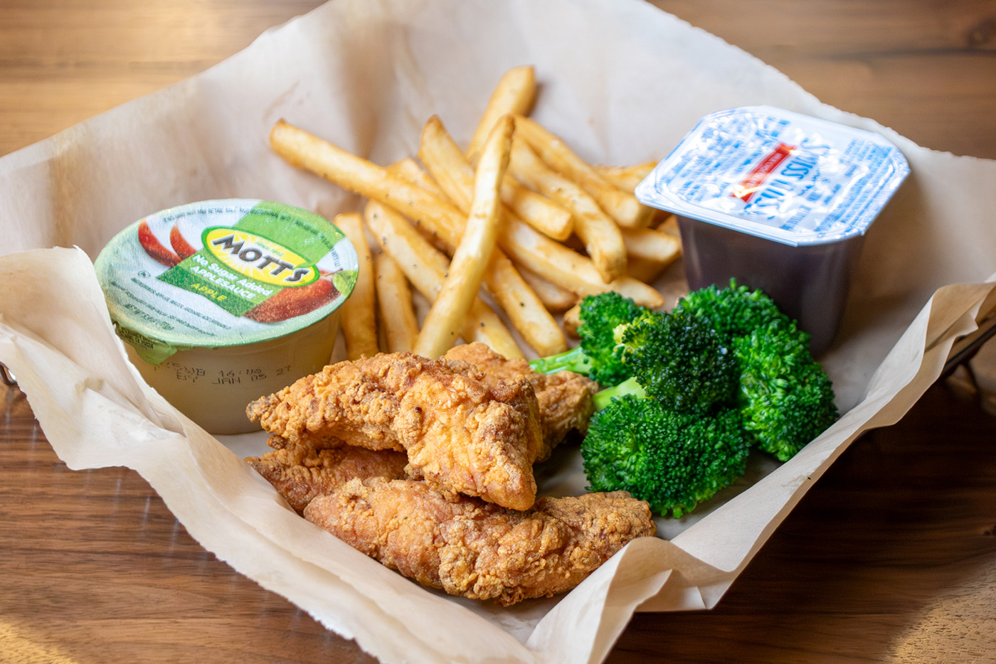 Kids Meal with chicken tenders, side of broccoli, apple sauce, french fries and a pudding cup