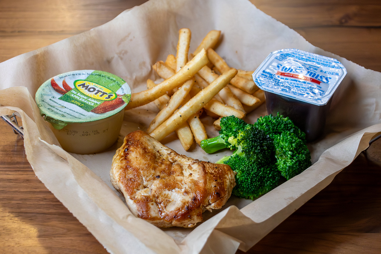 Kids Meal with grilled chicken, side of broccoli, apple sauce, fries and a pudding cup