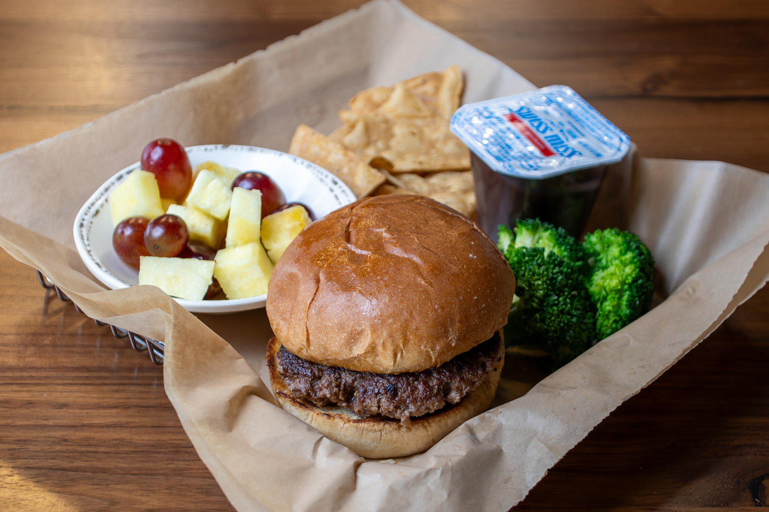 Kids Meal with a hamburger, side of broccoli, fruit, chips and a pudding cup