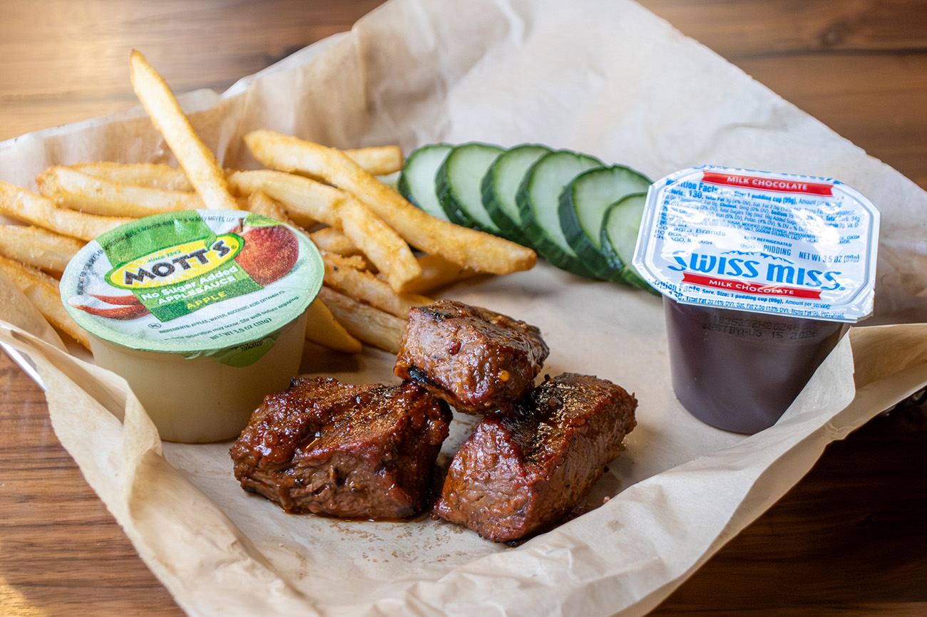Kids Meal with steak tips, side of sliced cucumbers, apple sauce, fries and a pudding cup