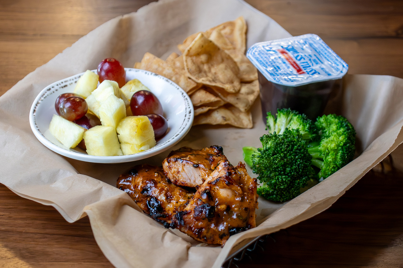 Kids Meal with turkey tips, side of broccoli, fruit, chips and a pudding cup