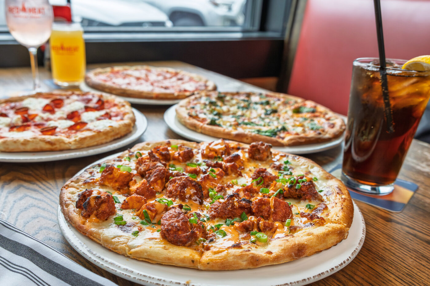 A pizza spread with buffalo chicken pizza, pepperoni ricotta & hot honey pizza, mediterranean pizza and a classic cheese pizza