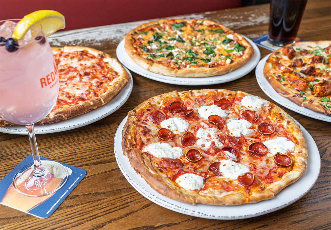 A pizza spread with buffalo chicken pizza, pepperoni ricotta & hot honey pizza, mediterranean pizza and a classic cheese pizza