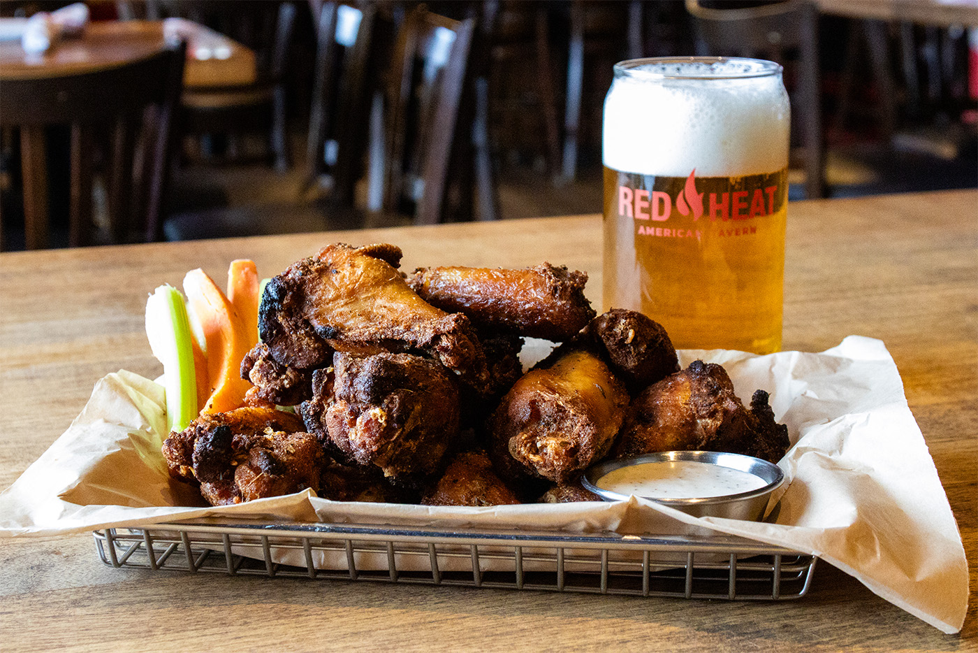 Wings with a side of celery, carrots and a beer on top of a wooden table